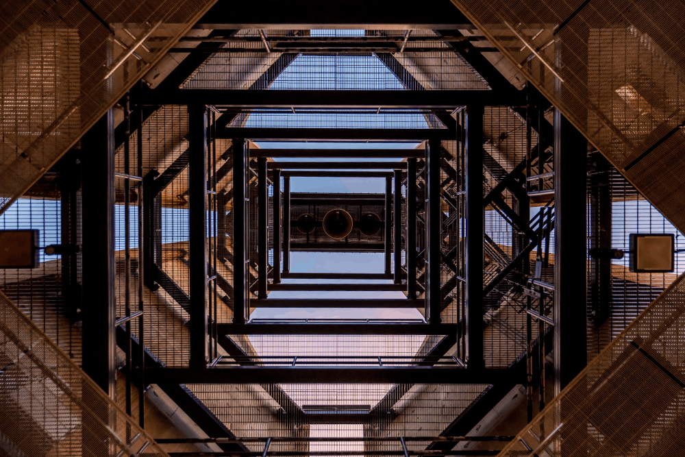 A black metal tower building in a low angle view
